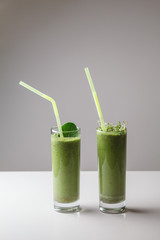 Freshly blended green fruit smoothie in glass with straw. Theme of raw food, live food, healthy eating background