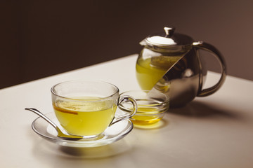 Herbal mint tea in a glass cup with lemon, the teapot and honey