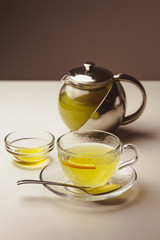 Herbal mint tea in a glass cup with lemon, the teapot and honey