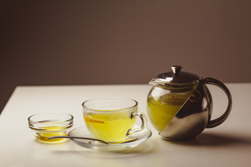 Herbal mint tea in a glass cup with lemon, the teapot and honey