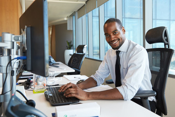 Fototapeta na wymiar Portrait Of Businessman At Office Desk Using Computer
