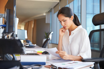 Businesswoman At Office Desk Reading Document