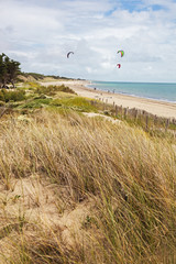 Kite surfing on the deserted Atlantic beach  on the island of Ile de Re with dunes covered with grass in the foreground, France
