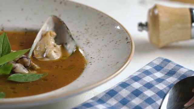 Tomato soup with seafood decorated with basil leaves and cherry tomatoes in white plate on the table.