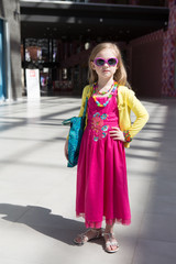 Obraz premium Cheerful preschool girl walking with shopping bags. child in dress, sunglasses near shopping mall having fun.