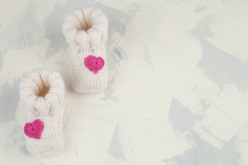 white knitted baby booties with pink knitting heart, copy space