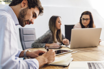 Group of young business people working at start-up in office with laptop and notepad