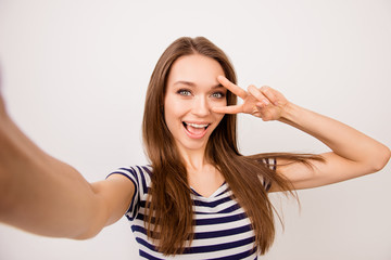Fototapeta premium Self-portrait of pretty laughing dreaming girl in striped t-shirt showing v-sign near her eyes