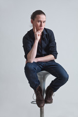 Junger Mann sitzend auf einem Hocker