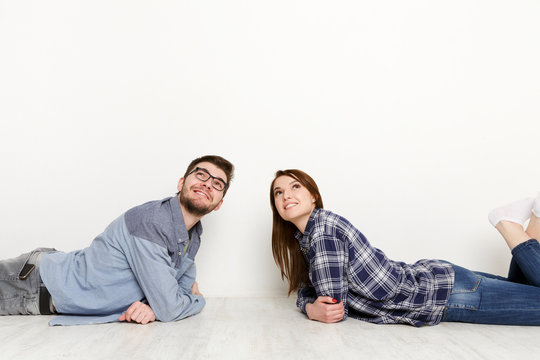 Dreamy couple lying on floor in empty room