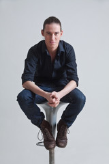 Junger Mann sitzend auf einem Hocker