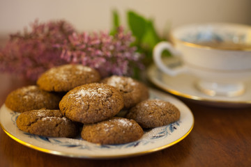a plate of Molasses cookies with green tea in a vintage porcelain teacup with purple flowers 