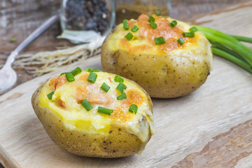 Close up of a hot baked potato topped with sour cream, bacon, green onions and cheddar cheese.