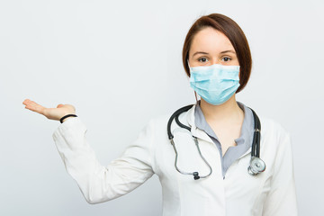 Beautiful successful female doctor with medical mask holding something on her hand