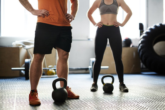 Unrecognizable man and woman having fitness training with kettlebells in gym