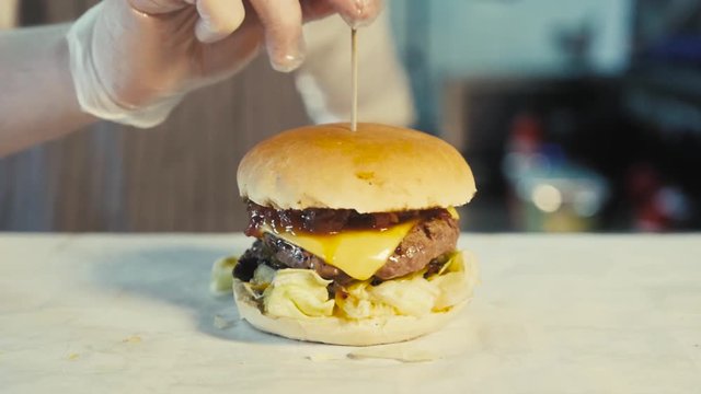 A picture of a big tasty bitten burger outdoors in cafe kitchen, chef with juicy hambugrer, healthy fast food