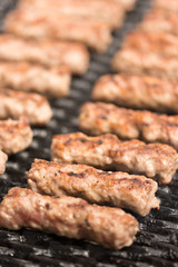 Grilling minced meat kebabs on the barbecue with selective focus