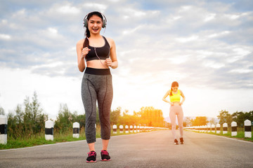 Runners - two women running outdoors training. Exercising female athletes jogging outside on nature smiling happy. Multiracial Asian and Caucasian woman in healthy lifestyle.