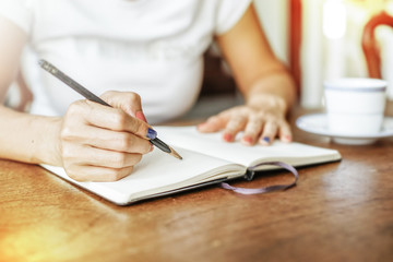 Asian women with pencil and empty note on wooden teble.