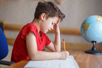 Sad child working on hard homework at home alone
