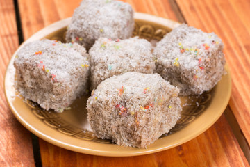 Chocolate cookies with coconut served on the plate over wooden background