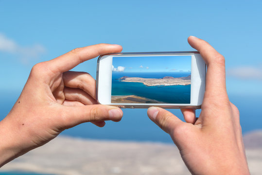 Close up on hands holding a smartphone to take pictures, in Lanzarote, Spain