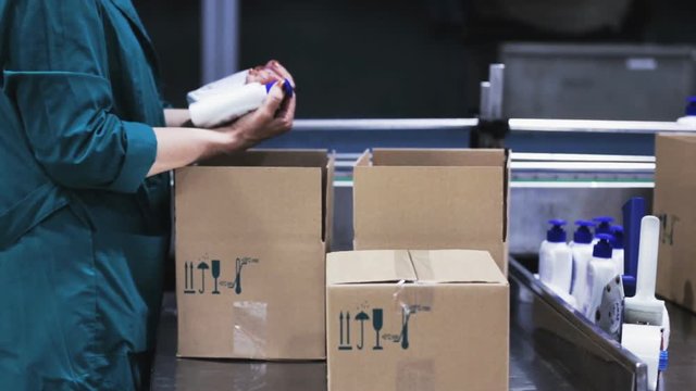 Worker takes the bottles from the conveyor belt and puts them in a box