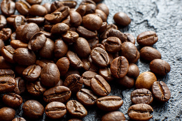 Grains of coffee are scattered on a black stone