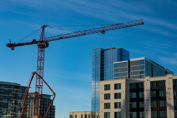 Construction crane and new buildings against blue sky