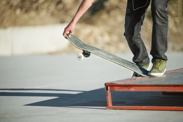 Obraz na płótnie Canvas A young guy on a skateboard in a manual on a skatepark on the background of house