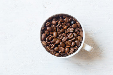 Coffee cup full of coffee beans on white  background