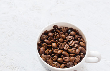 Coffee cup full of coffee beans on white  background