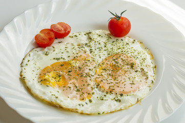 fried eggs on a plate with tomatoes and chopped parsley