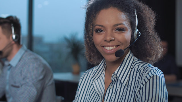 Woman Talking To The Client With Headset And Smiling While Looking At Camera.
