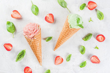 Summer fresh desserts. Green basil and red strawberry ice cream in a cone. On a white stone table with basil leaves and fresh strawberries around. On a white stone table. Copy space