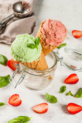 Summer fresh desserts. Green basil and red strawberry ice cream in a cone. On a white stone table with basil leaves and fresh strawberries around. On a white stone table. Copy space