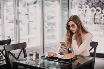 Woman having breakfast and using her mobile phone