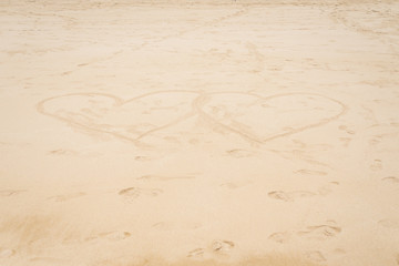 Two huge hearts on a sandy tropical beach. Palms, sand and blue sky on the ocean.