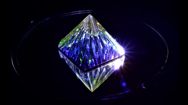 Pyramid of colored glass on a black background with a mirror image on the bottom