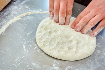 Hands rolling out dough in flour for print