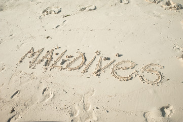 Inscription Maldives on white sand. Maldives