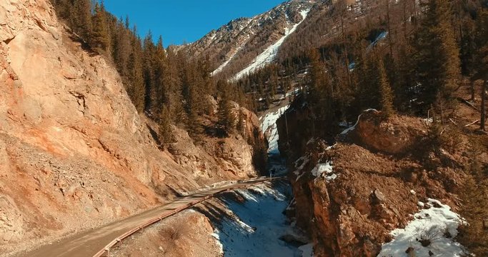The road between the mountains. Car road between capped trees. Serpentine road between the terracotta mountains. A beautiful natural landscape: a reserve in the Altai Mountains.