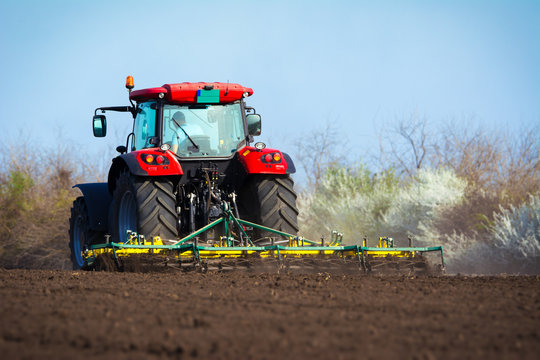 Fototapeta Farmer in tractor preparing land with seedbed cultivator