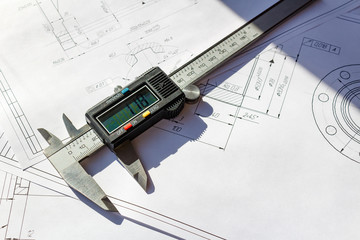 Digital caliper lies on a engineering drawings