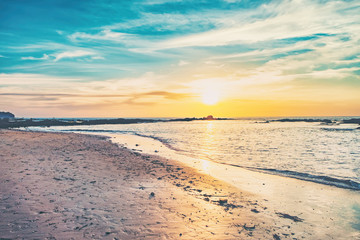 Coast of the sea at colorful sunset, Nang Thong Beach, Andaman Sea, Khao Lak, Thailand. Beach sunset is a golden sunset sky with a wave rolling to shore as the sun sets over the ocean horizon.