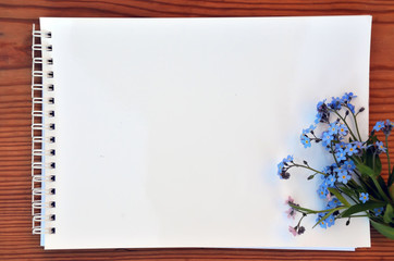 Blank page of a notebook and bouquet of forget-me-nots