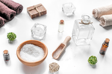 spa cosmetics with soap, salt, oil, towels, candles on white background