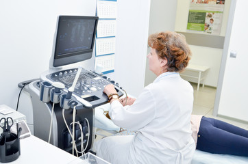 The doctor conducts ultrasound examination of the girl in the clinic's office on special medical...