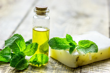cosmetic oil in bottle and soap with herbs on light table background