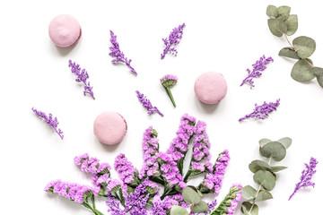 macaroons and flowers for light breakfast on white desk background top view